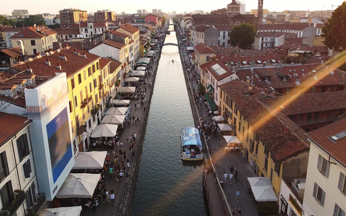 Navigli canal cruise boat in Milan with bustling streets and historic buildings.