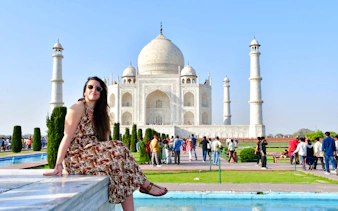 Visitor sitting near the Taj Mahal with tourists in Agra, India.