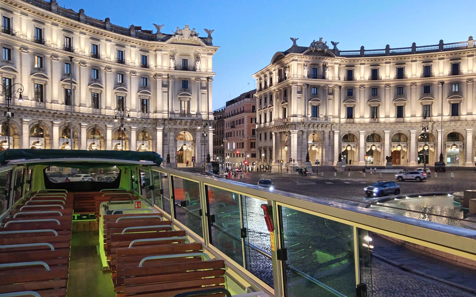Open-top vintage bus in Rome's Piazza della Repubblica at dusk.