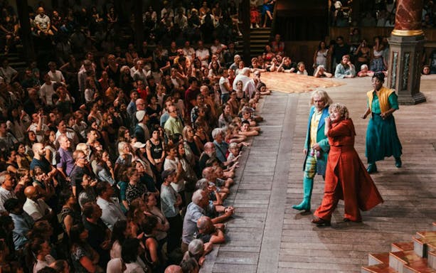 Actors performing "Twelfth Night" on stage with audience at Shakespeare's Globe Theatre.