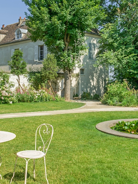 Montmartre Museum garden with white table, chairs, and pond in Paris.