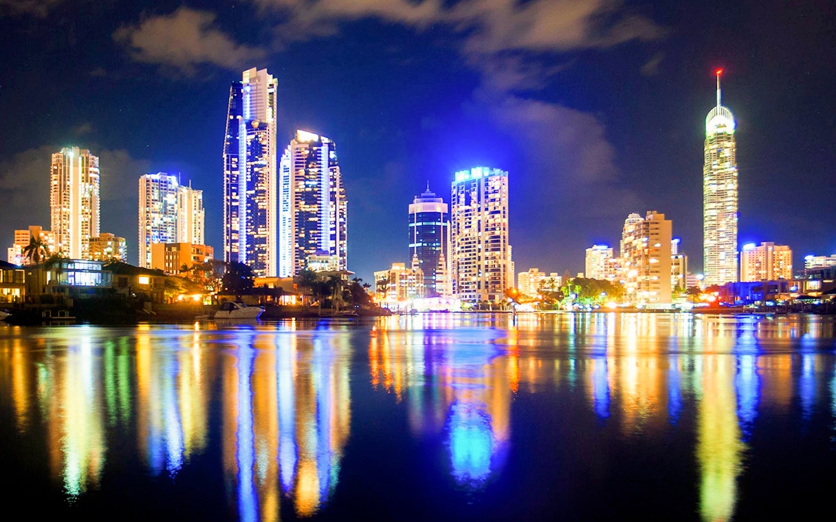 City skyline illuminated at night, viewed from a buffet dinner cruise on the water.