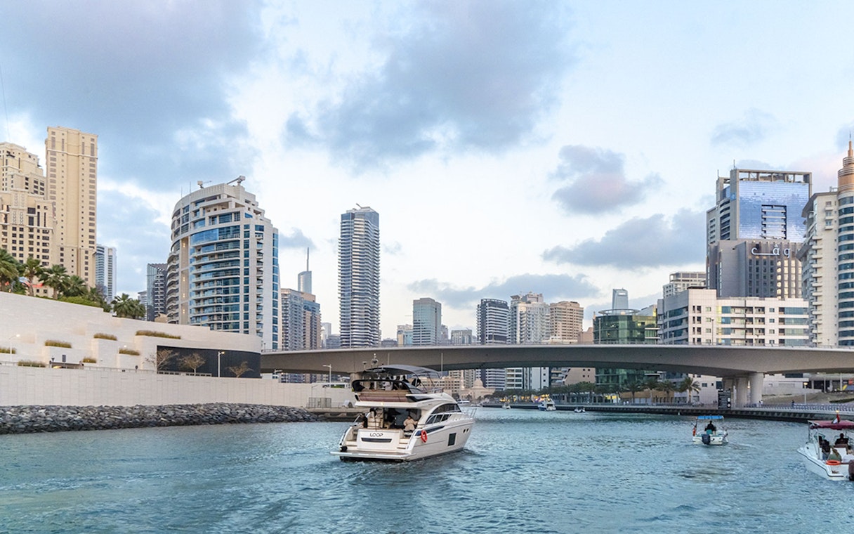 Luxury yacht cruising through Dubai Marina with city skyline in the background.