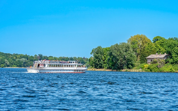 Cruise ship on the Greater Wannsee heading towards Peacock Island, surrounded by lush greenery.