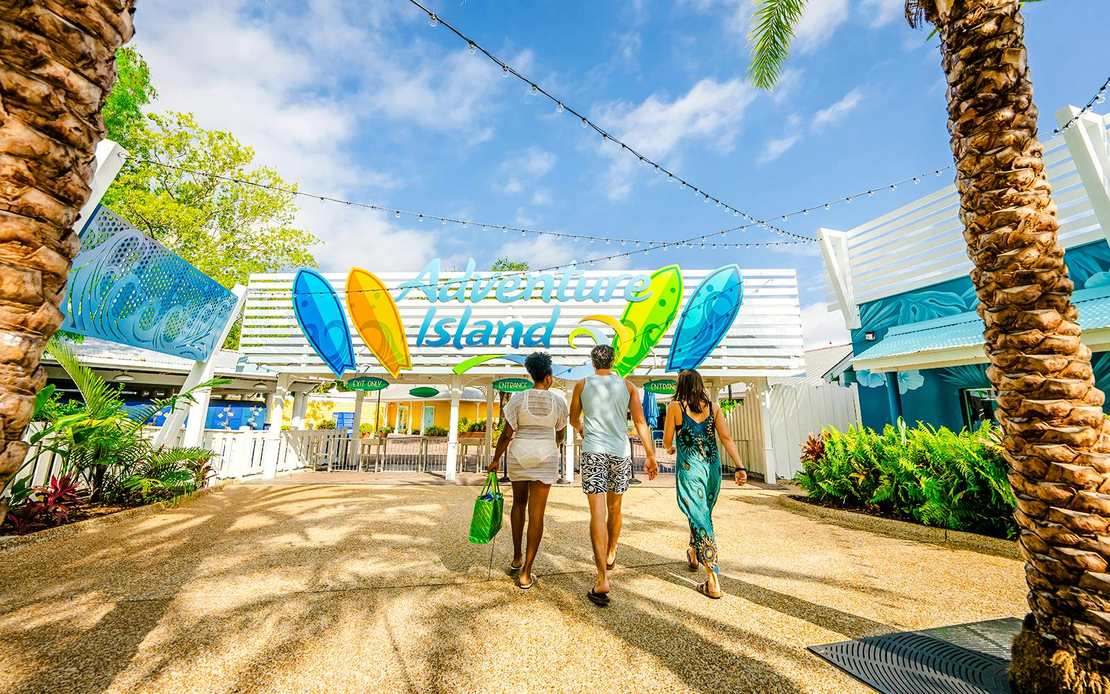 Visitors entering Adventure Island water park in Tampa under a colorful sign.