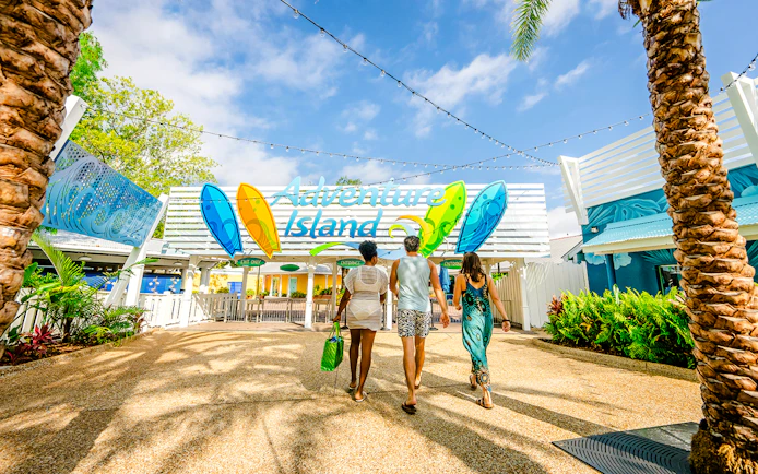 Visitors entering Adventure Island water park in Tampa under a colorful sign.