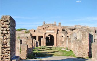 Ostia Antica ruins with ancient brick structures and archway, Rome.