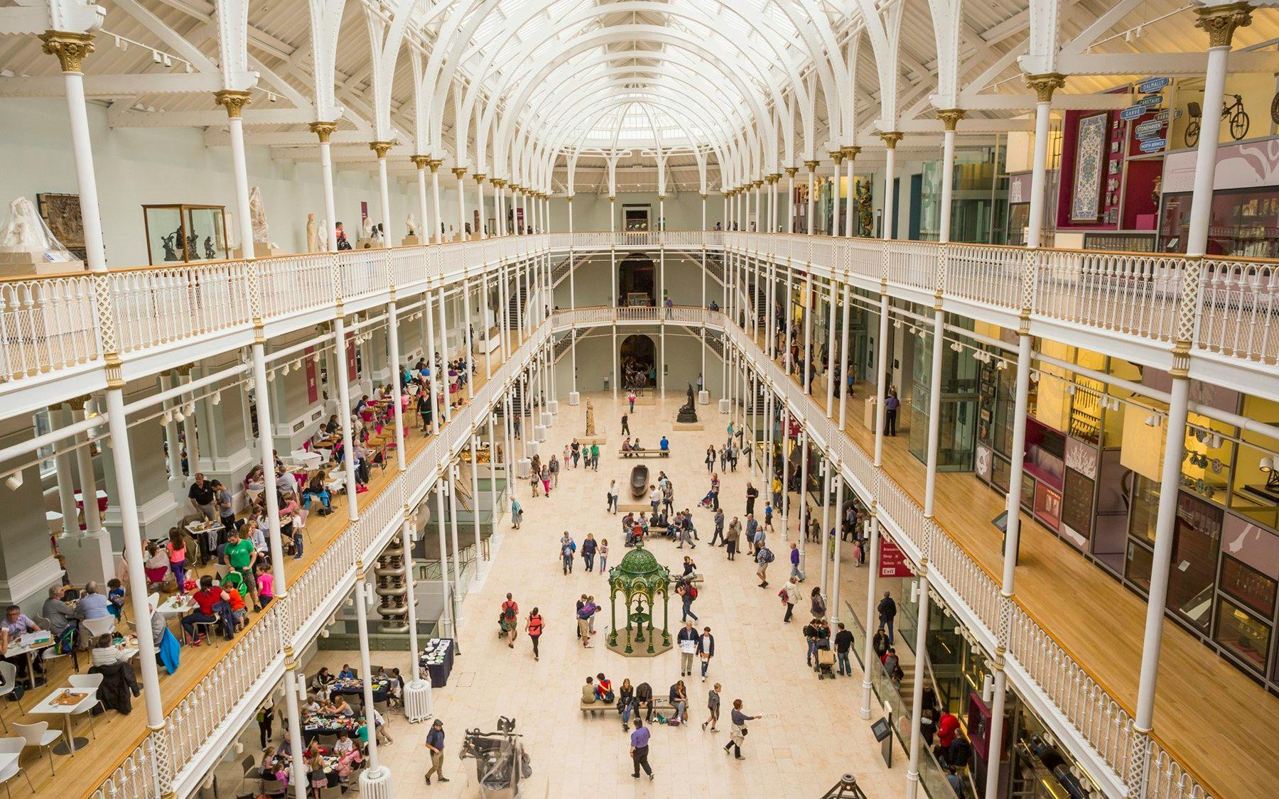Visitors exploring the grand atrium of a museum with multiple levels and exhibits.