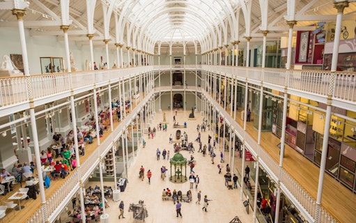 Visitors exploring the grand atrium of a museum with multiple levels and exhibits.