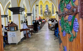 Interior of a church in Zanzibar with people attending a service, visible ornate wooden door.