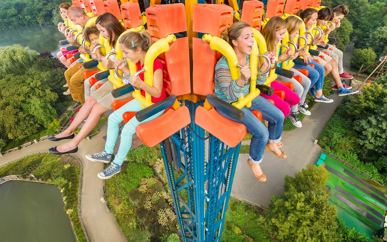 People enjoying the Screaming Eagle ride, high above a lush park landscape.