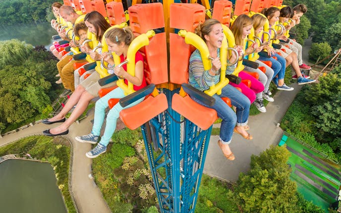 People enjoying the Screaming Eagle ride, high above a lush park landscape.
