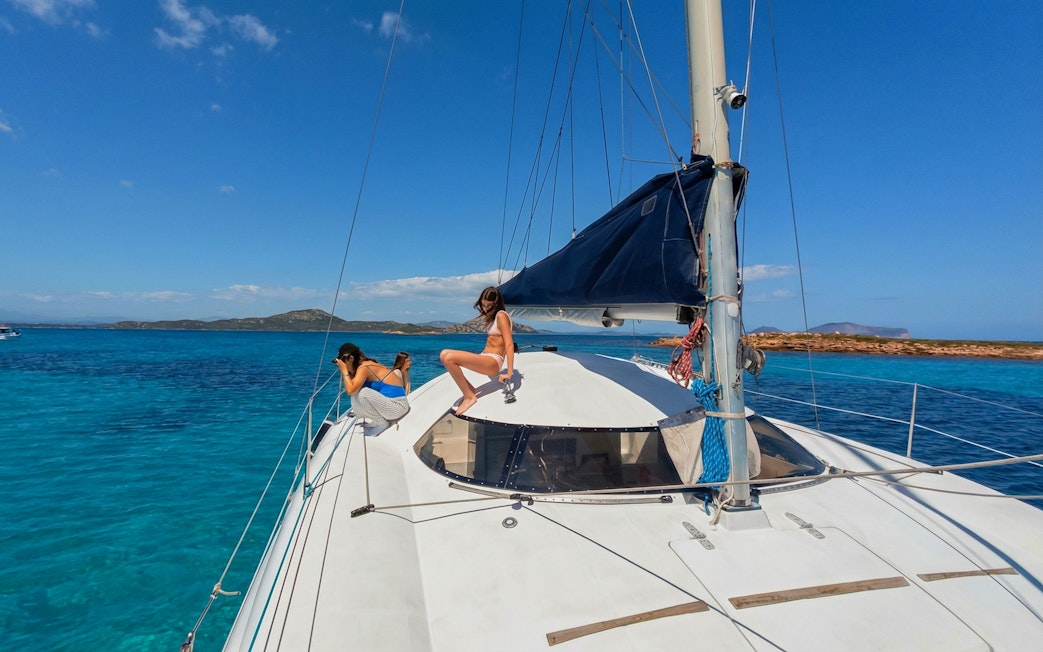 Catamaran sailing near Tavolara Island with passengers enjoying the view.