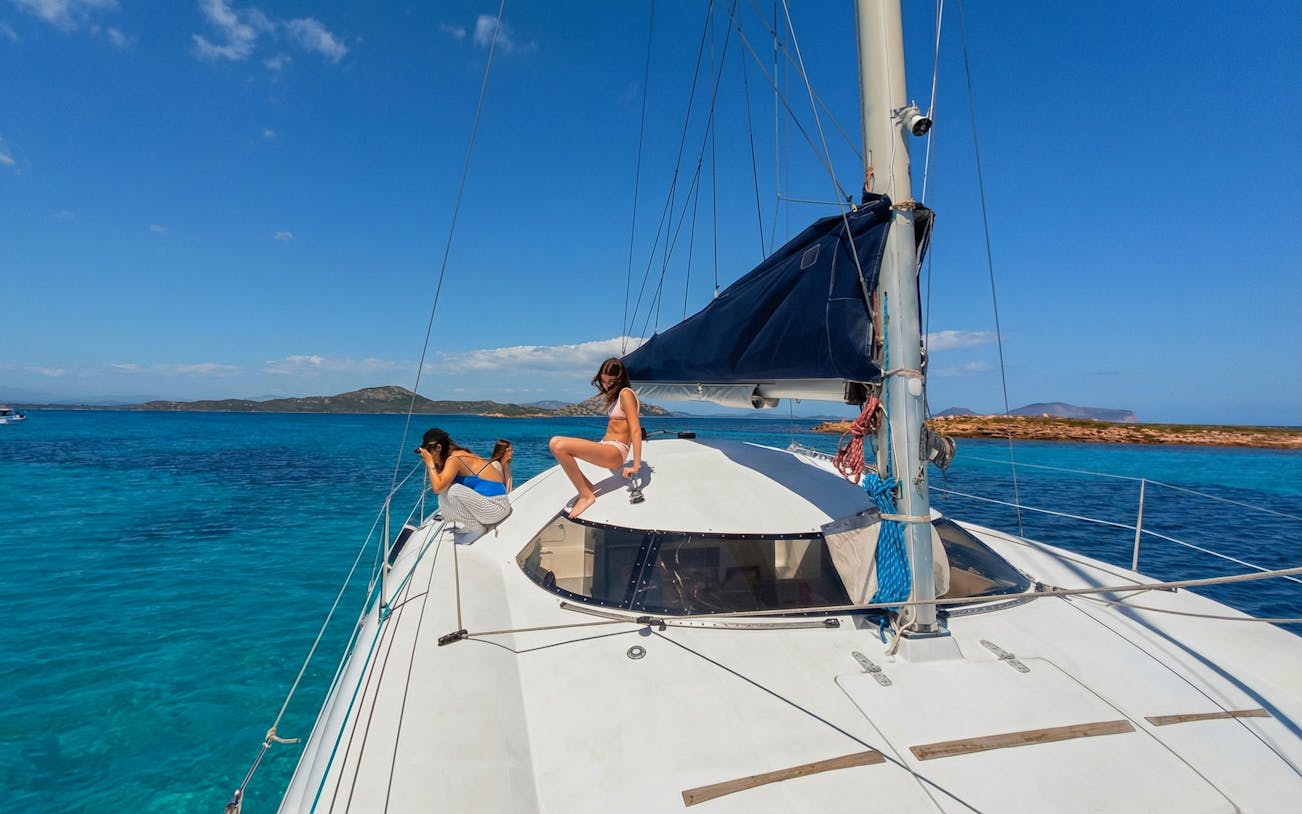 Catamaran sailing near Tavolara Island with passengers enjoying the view.