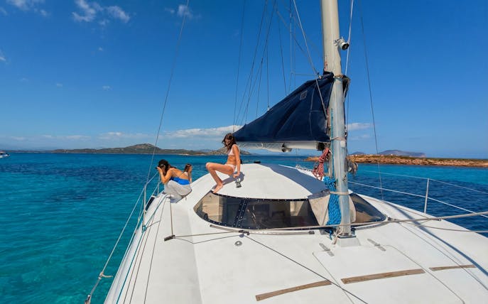 Catamaran sailing near Tavolara Island with passengers enjoying the view.