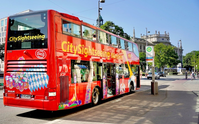 CitySightseeing bus in Munich near historic building.