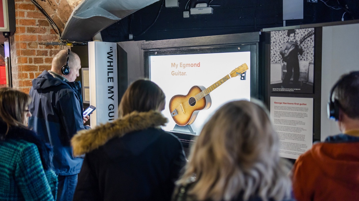 Visitors viewing George Harrison's first guitar exhibit at The Beatles Story.