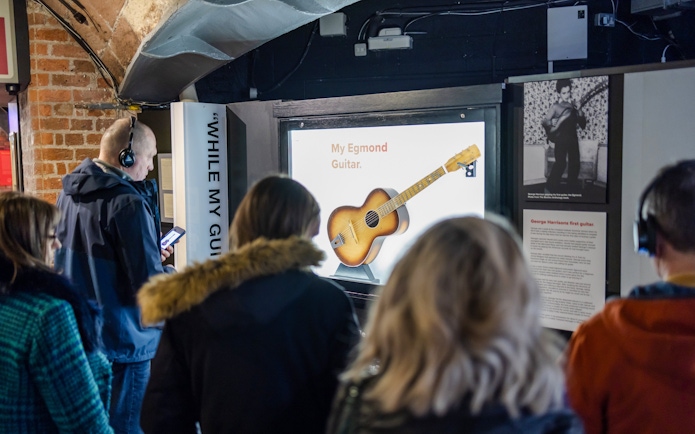 Visitors viewing George Harrison's first guitar exhibit at The Beatles Story.