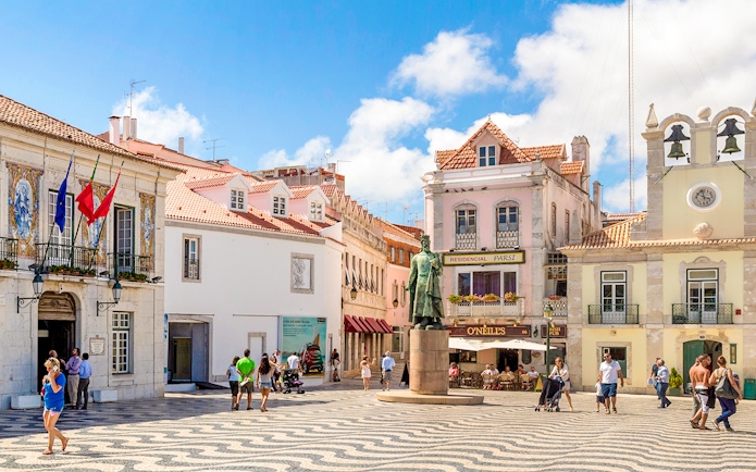 Cascais main square with statue, historic buildings, and people walking.