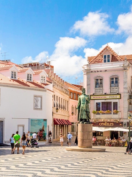 Cascais main square with statue, historic buildings, and people walking.