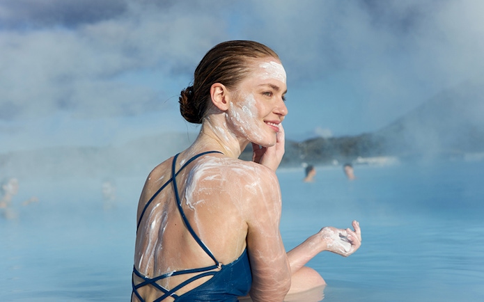 Tourist applying silica mud in Blue Lagoon, Iceland.