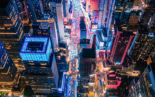 Aerial view of New York City skyscrapers and streets illuminated at night during helicopter tour.