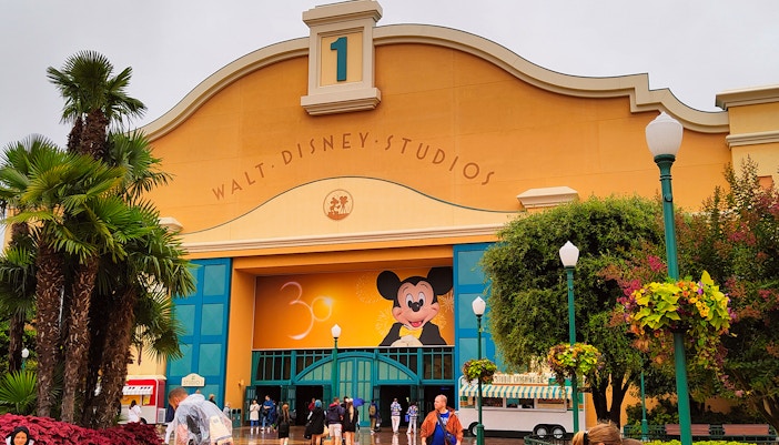 Walt Disney Studios entrance with Mickey Mouse mural and visitors in front.