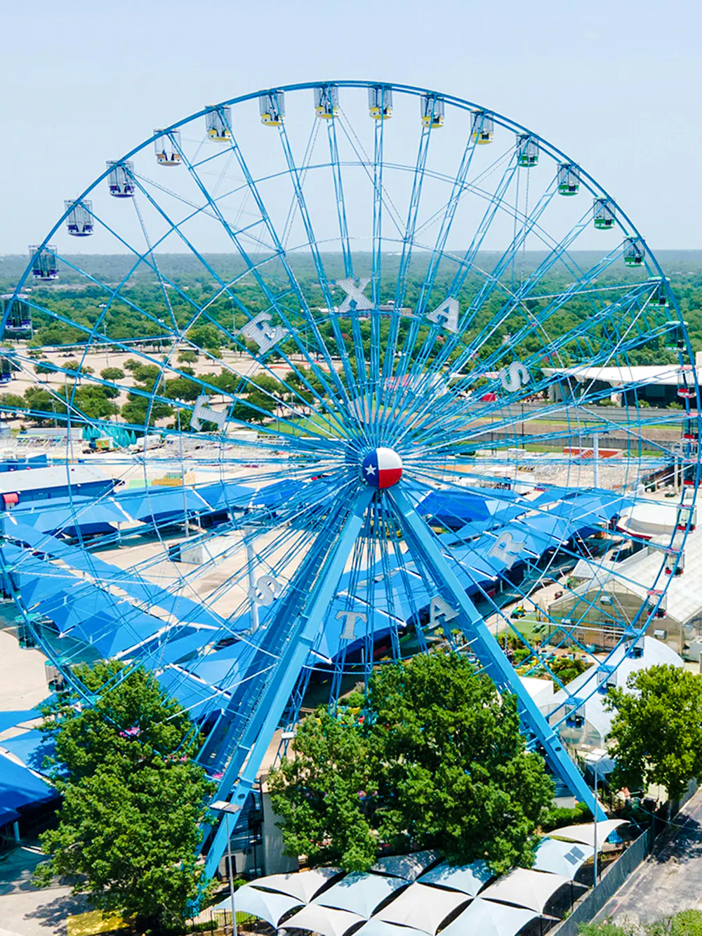 State Fair of Texas Ferris Wheel with blue gondolas and Texas flag emblem.