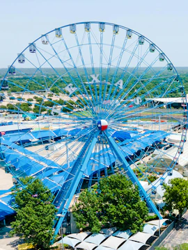 State Fair of Texas Ferris Wheel with blue gondolas and Texas flag emblem.