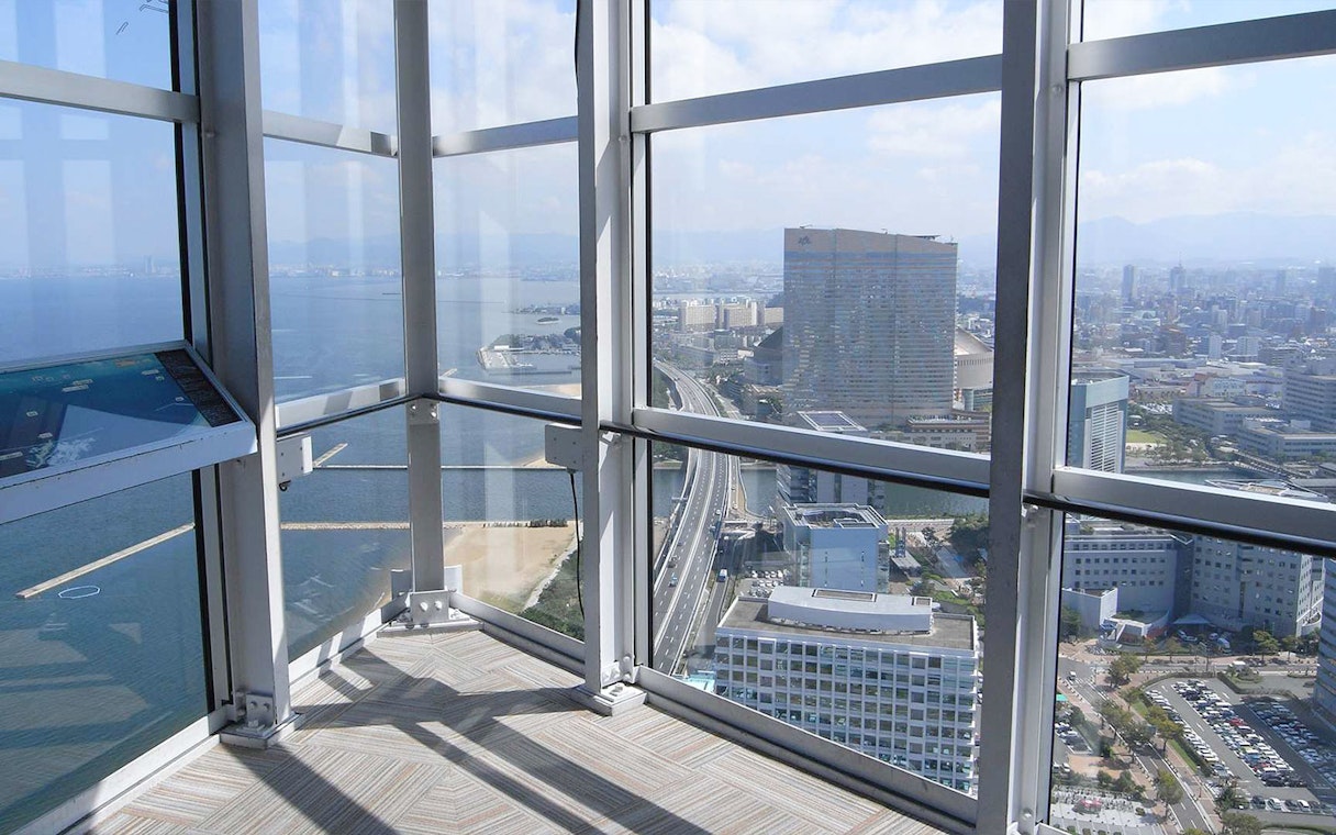 View from Fukuoka Tower observation deck overlooking cityscape and coastline.