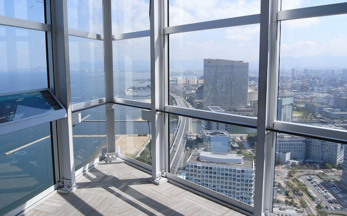 View from Fukuoka Tower observation deck overlooking cityscape and coastline.