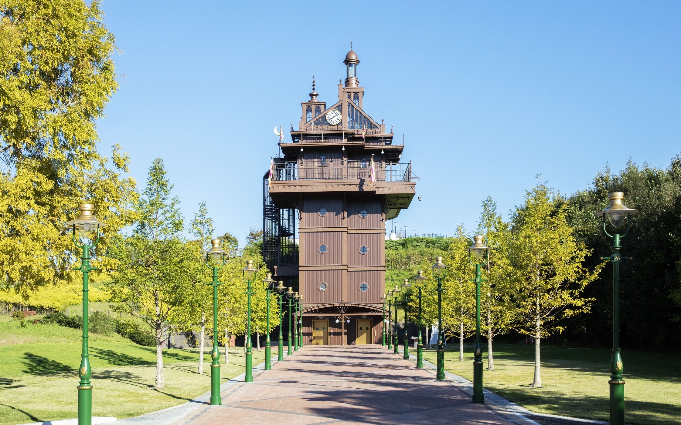 Ghibli Park tower with green lampposts and trees lining the pathway.