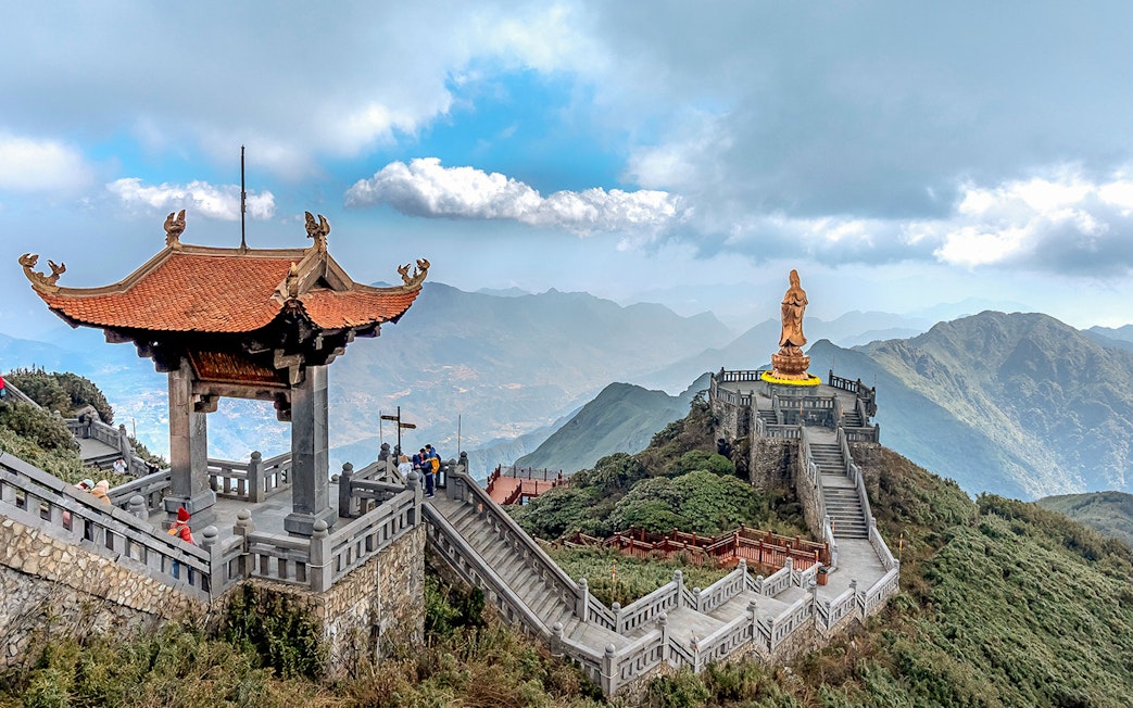 Pagoda and statue on Fansipan mountain peak, Vietnam, with scenic mountain views.