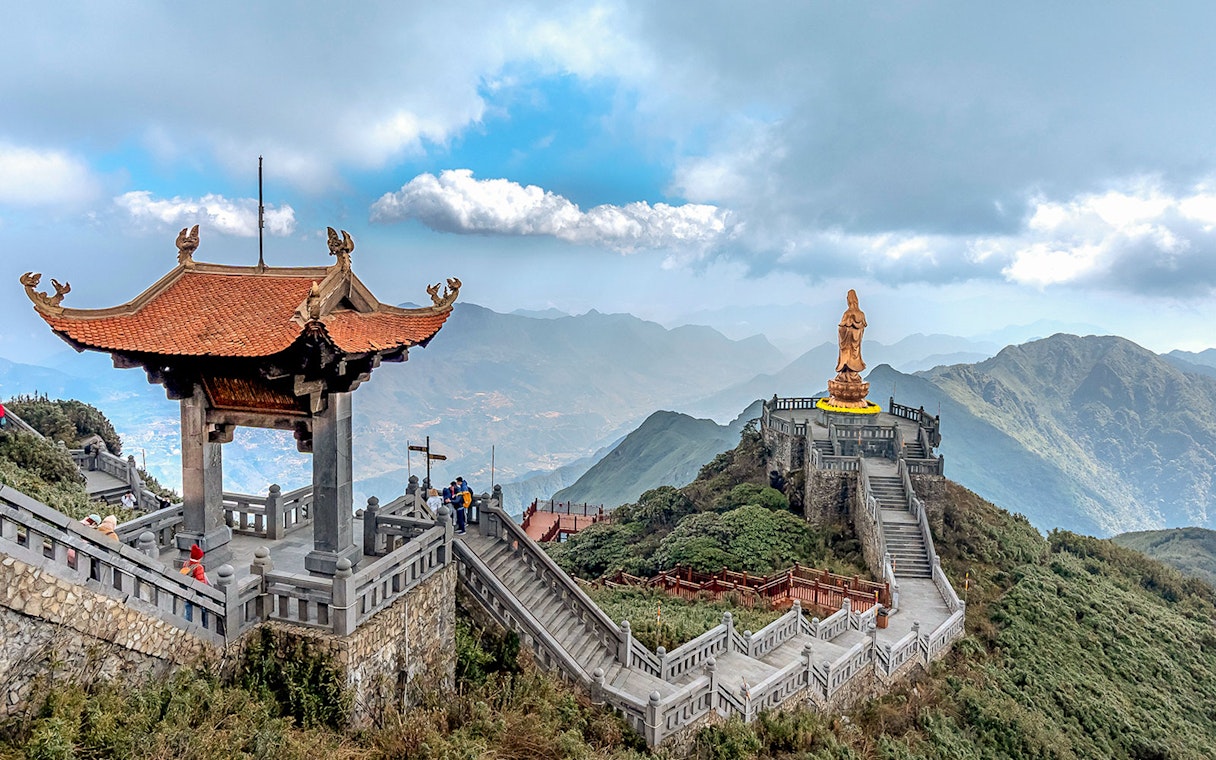 Pagoda and statue on Fansipan mountain peak, Vietnam, with scenic mountain views.