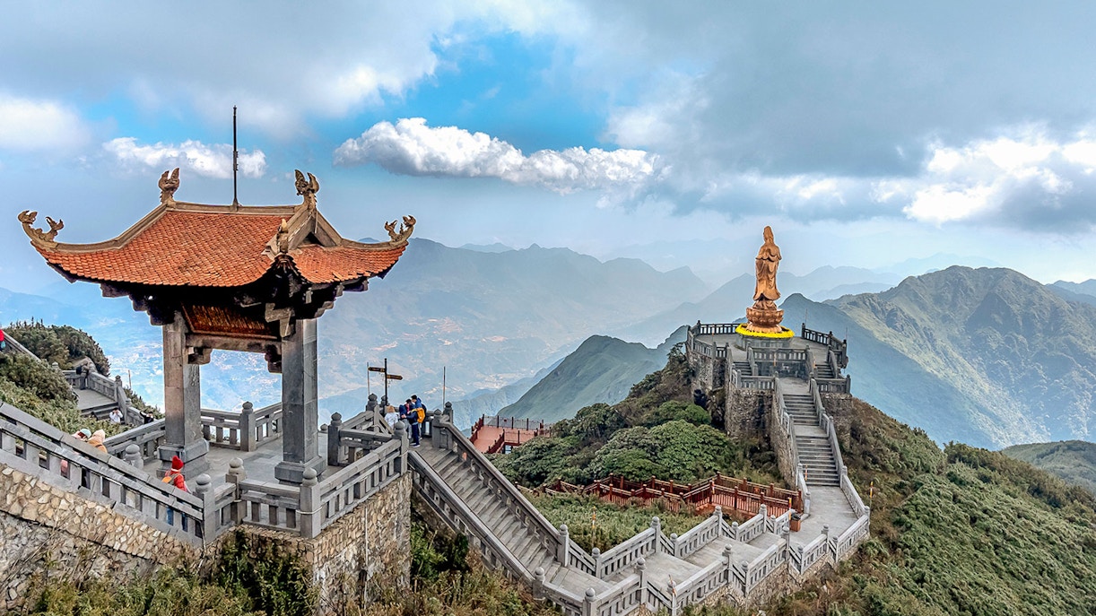 Pagoda and statue on Fansipan mountain peak, Vietnam, with scenic mountain views.
