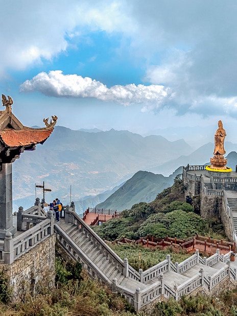 Pagoda and statue on Fansipan mountain peak, Vietnam, with scenic mountain views.
