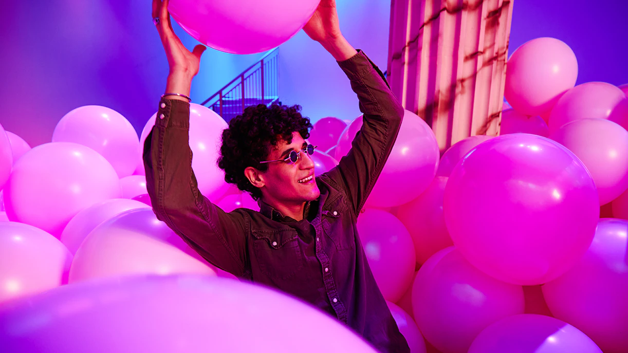 Person enjoying pink balloons at Bubble Planet exhibit, Washington DC.