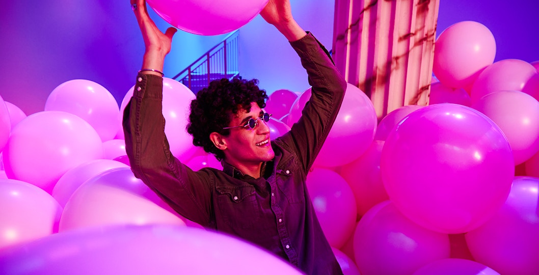 Person enjoying pink balloons at Bubble Planet exhibit, Washington DC.