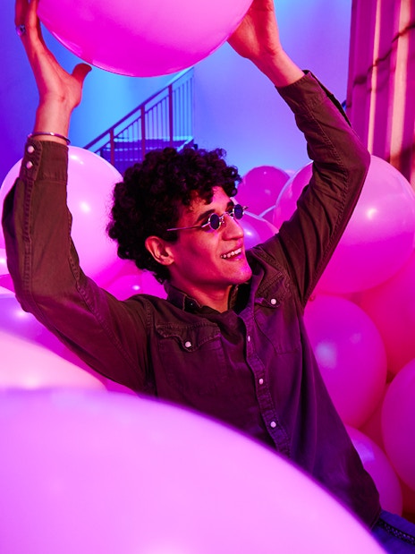 Person enjoying pink balloons at Bubble Planet exhibit, Washington DC.