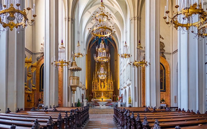 Interior of The Augustinian Church with ornate chandeliers and a grand altar.