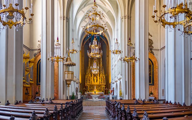 Interior of The Augustinian Church with ornate chandeliers and a grand altar.