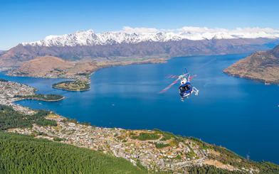 Helicopter flying over Lake Wakatipu with snow-capped mountains near Queenstown, New Zealand.