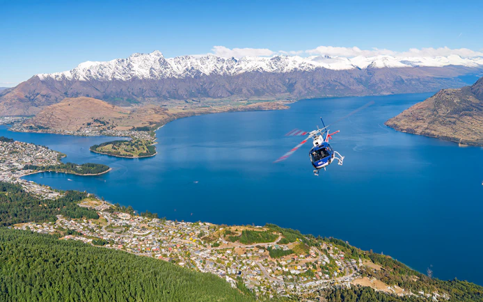 Helicopter flying over Lake Wakatipu with snow-capped mountains near Queenstown, New Zealand.