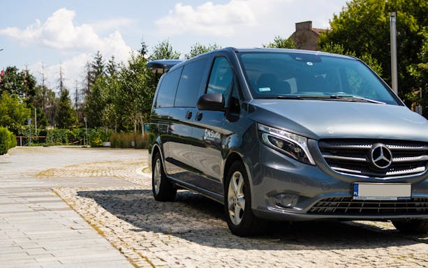 Krakow airport transfer van parked on cobblestone street.