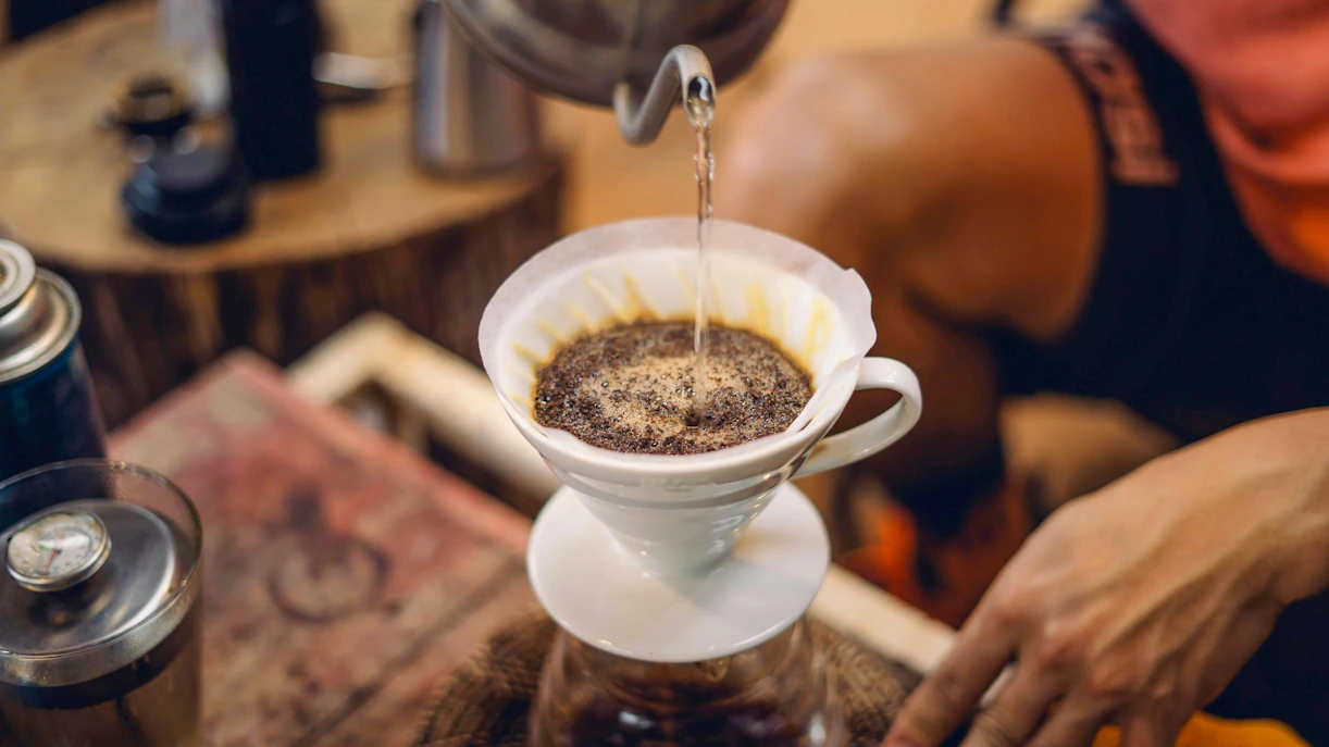Pouring hot water over ground coffee in a filter for brewing.
