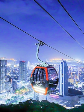 Kobe Nunobiki Ropeway gondola over cityscape at night.