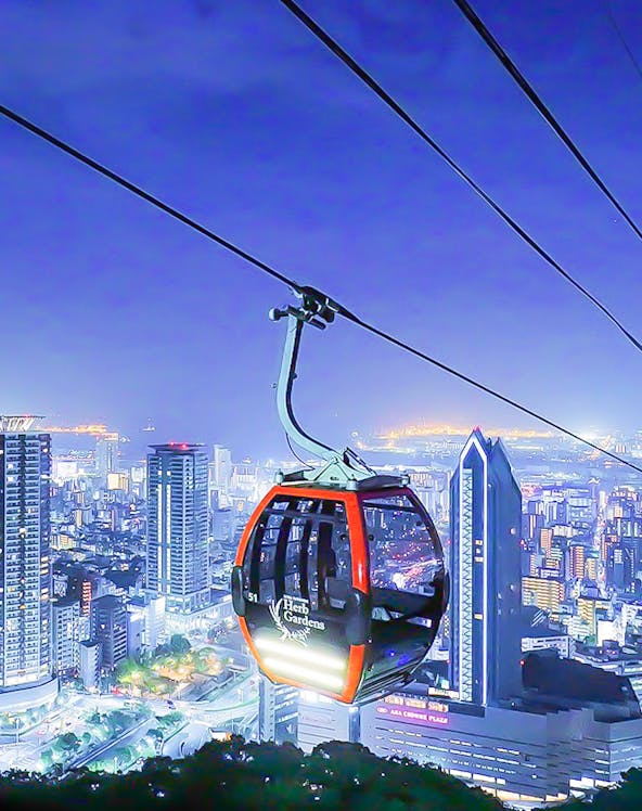 Kobe Nunobiki Ropeway gondola over cityscape at night.