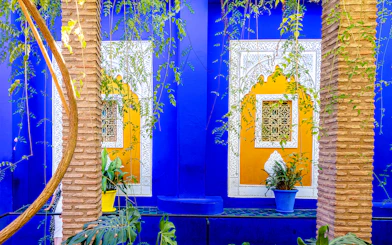 Jardin Majorelle's vibrant blue and yellow walls with intricate window designs and lush greenery.