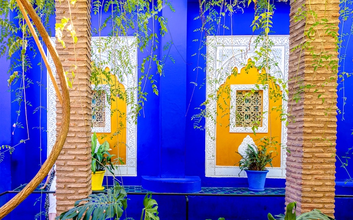 Jardin Majorelle's vibrant blue and yellow walls with intricate window designs and lush greenery.
