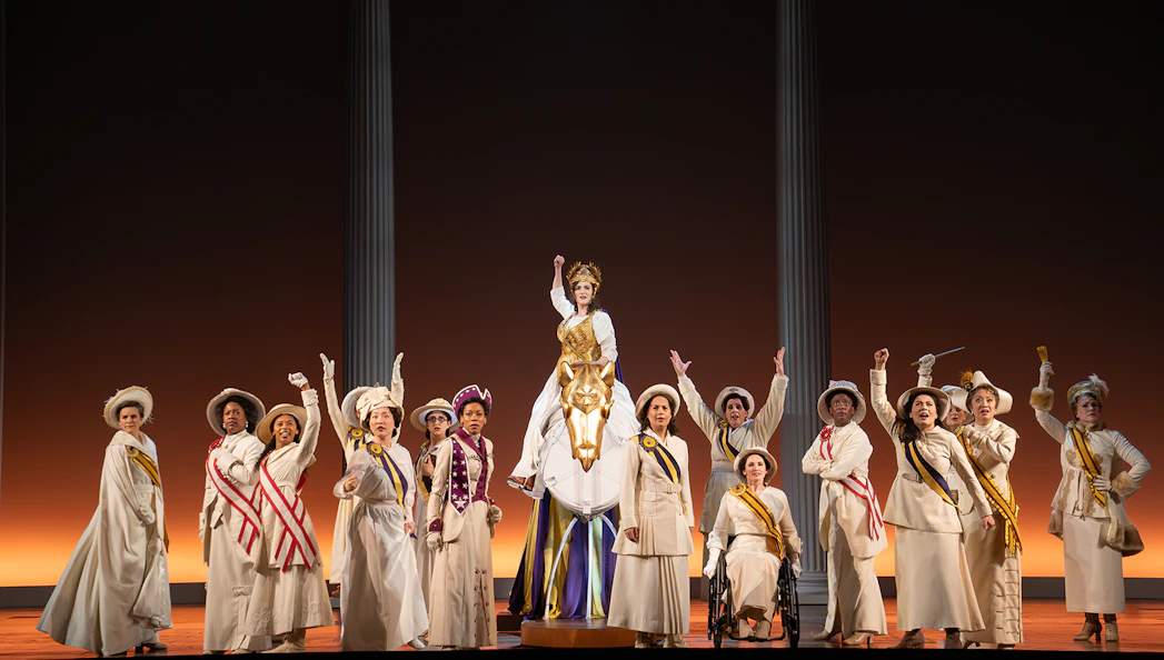 Performers in period costumes on stage during the show "Suffs" with a central figure on a horse.